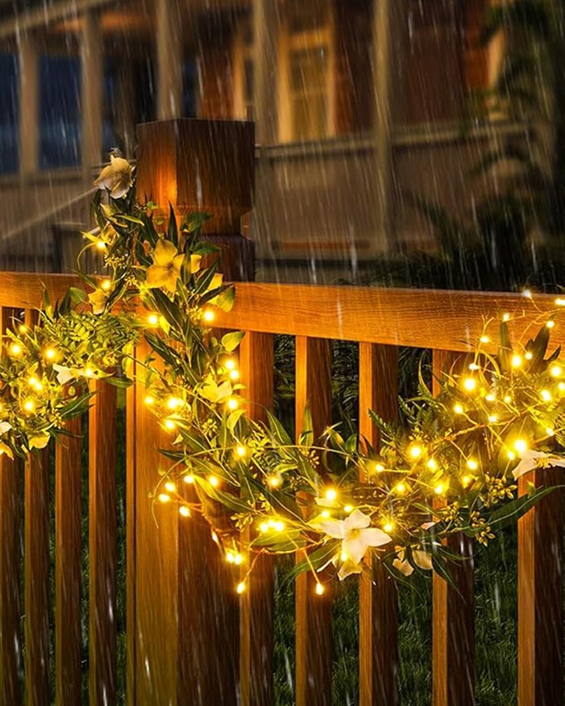 Warmweiße LED-Lichterkette an einer Holzbrüstung im Regen